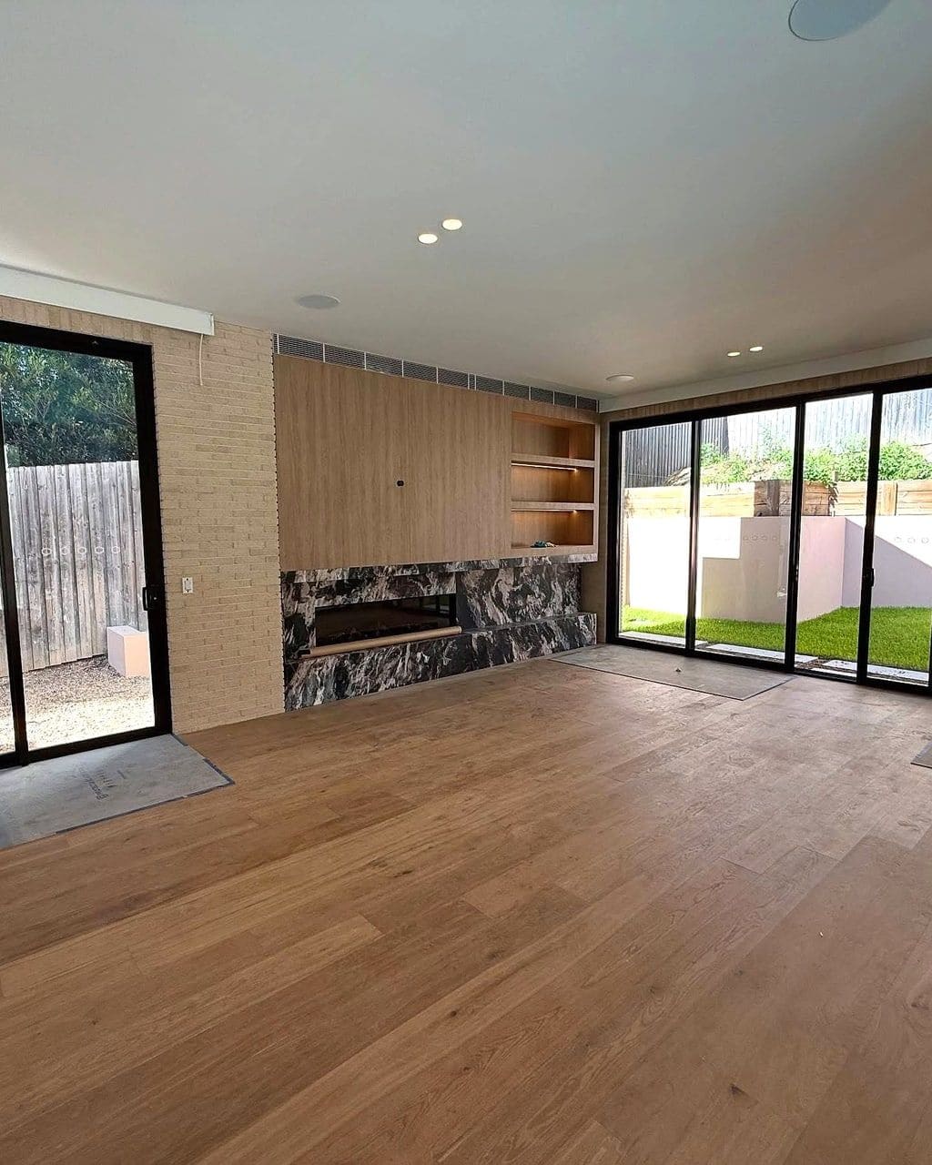 Wide oak planks laid in parallel runs across a living room with a stone fireplace