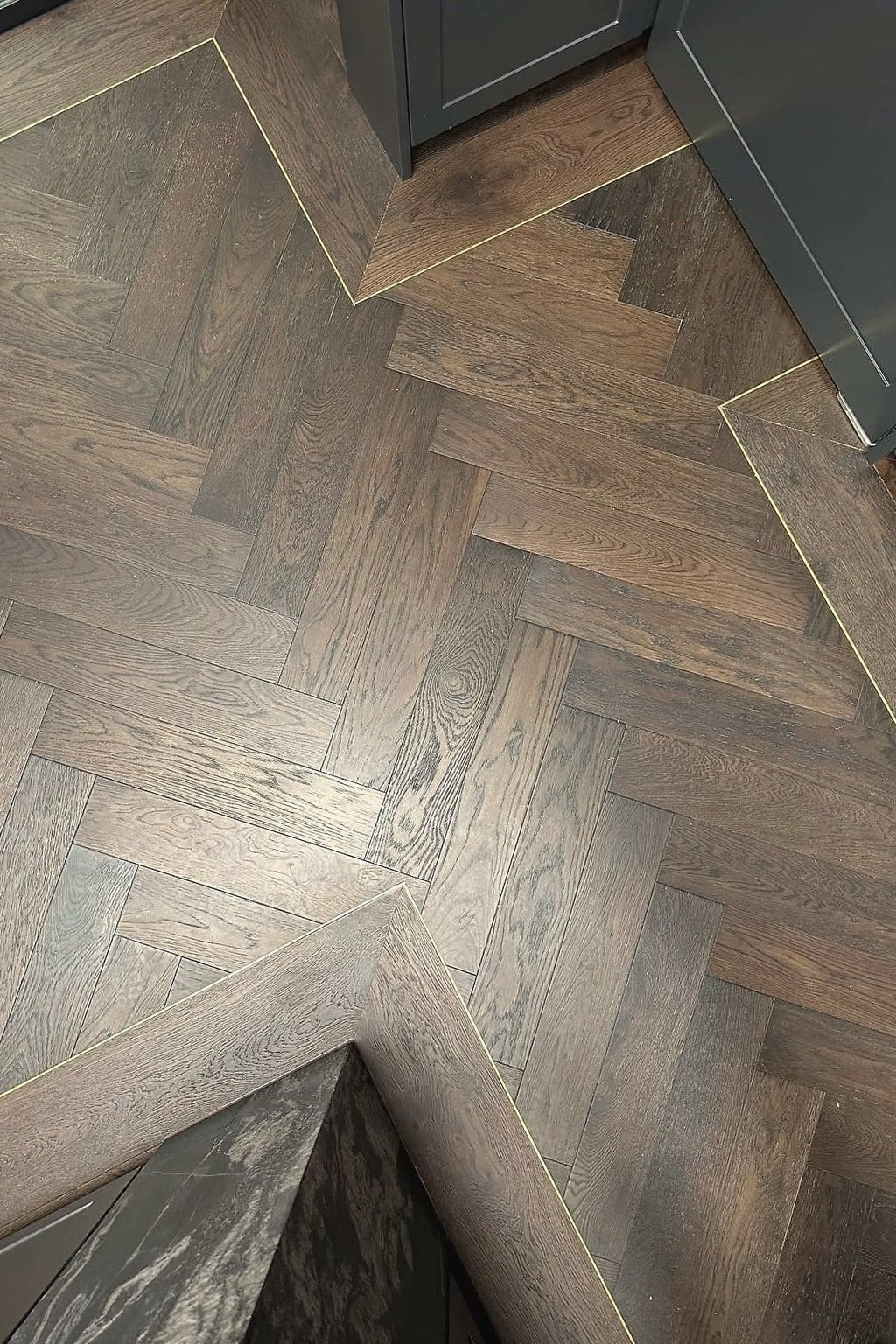 Dark smoked oak herringbone with a brass inlay strip set into the floor